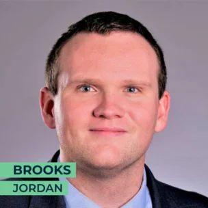 A man with short hair wearing a suit and tie. The text in the image reads "Brooks Jordan".