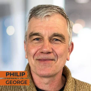 Portrait of a man with grey hair, wearing a tan sweater. Text overlay: "Philip George" on the bottom left of the image.