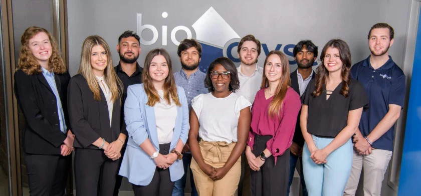 A group of eleven people standing together in a corporate office setting.